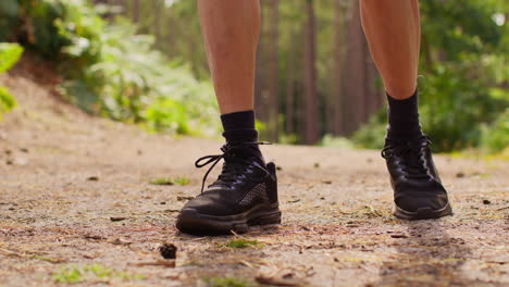 Close-Up-Of-Man-Tying-Laces-On-Training-Shoe-Before-Exercising-Running-Along-Track-Through-Forest